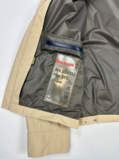 Prada beige Gore-Tex jacket packable into pocket, features logo and nylon material.