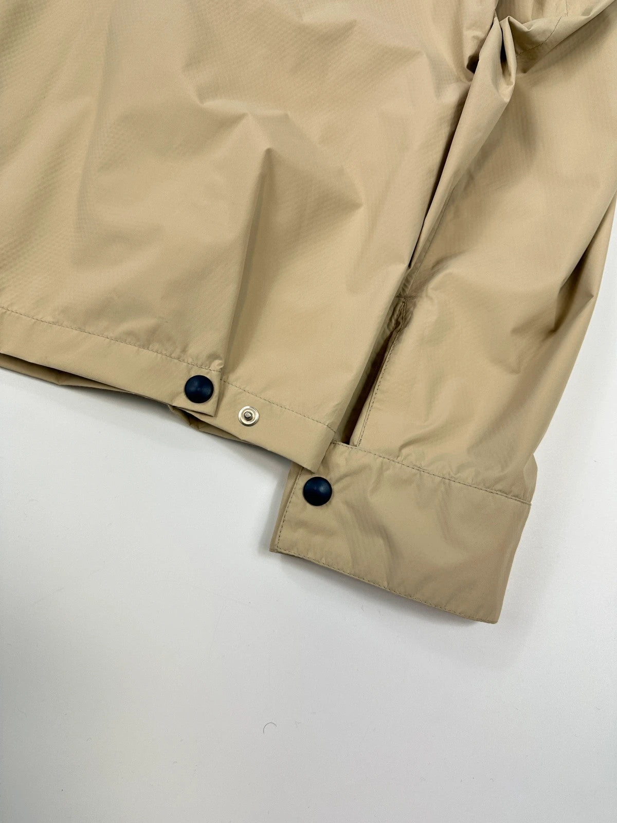 Prada beige Gore-Tex jacket packable into pocket, features logo and nylon material.
