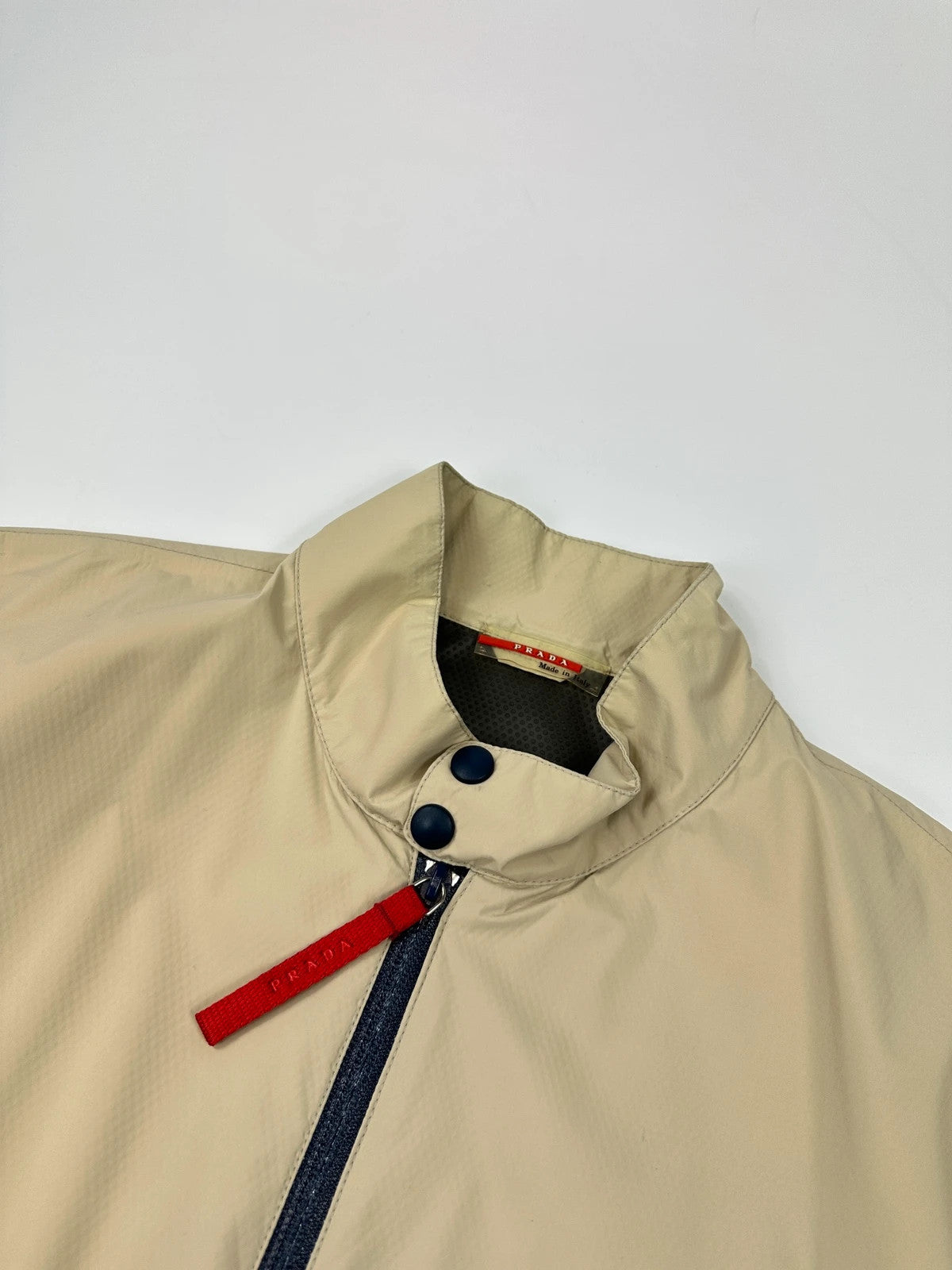 Prada beige Gore-Tex jacket packable into pocket, features logo and nylon material.