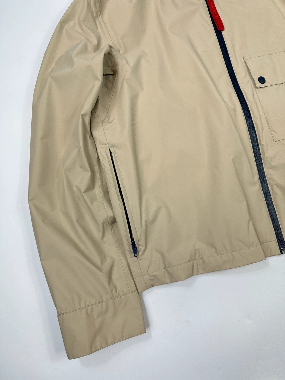 Prada beige Gore-Tex jacket packable into pocket, features logo and nylon material.