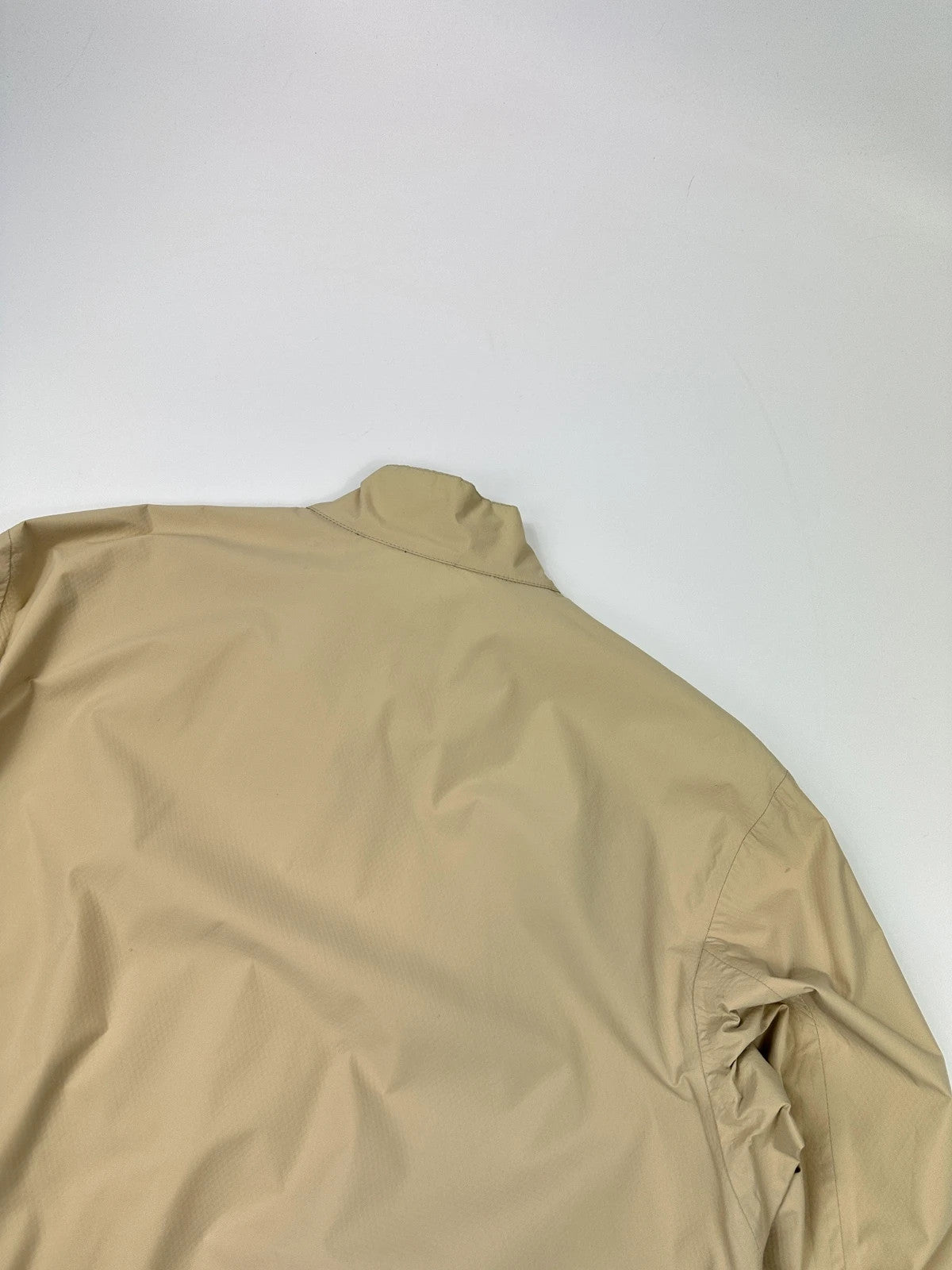 Prada beige Gore-Tex jacket packable into pocket, features logo and nylon material.