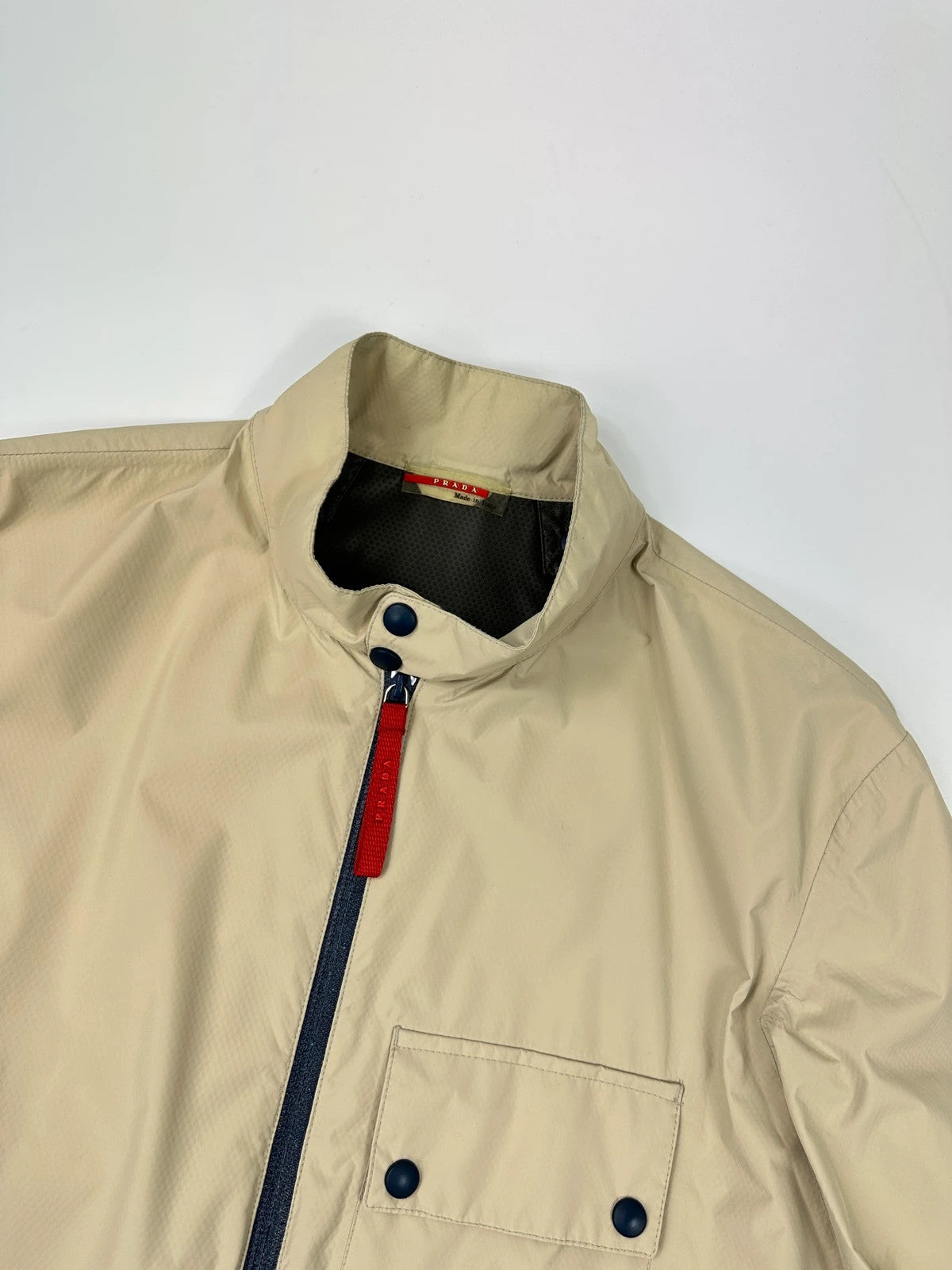 Prada beige Gore-Tex jacket packable into pocket, features logo and nylon material.