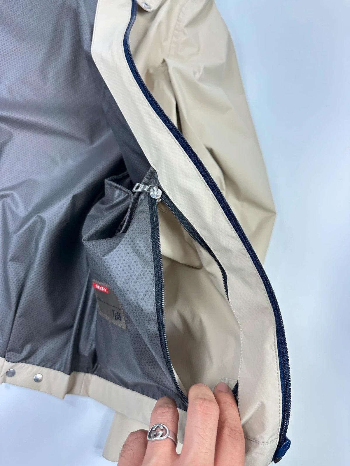 Prada beige Gore-Tex jacket packable into pocket, features logo and nylon material.