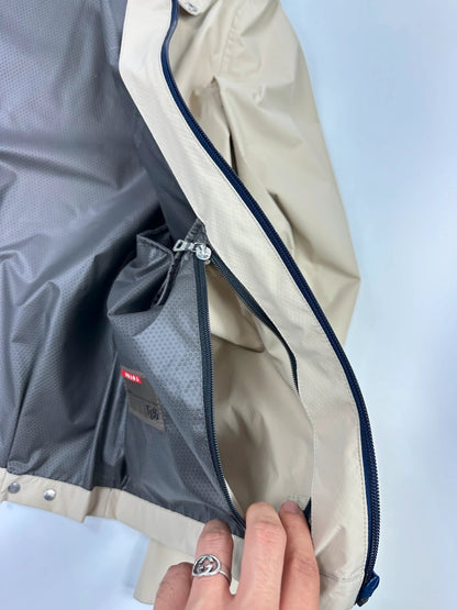 Prada beige Gore-Tex jacket packable into pocket, features logo and nylon material.