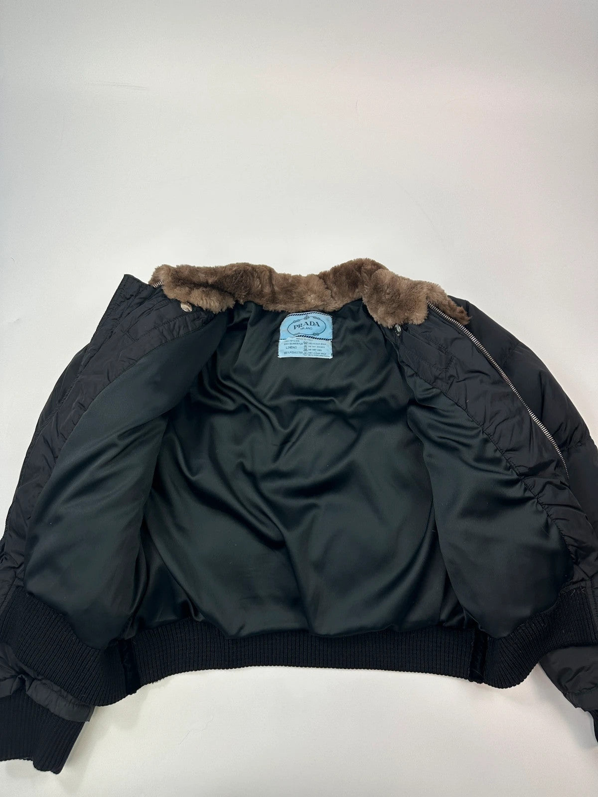 Prada black cropped bomber puffer jacket with logo detailing and vintage 90s design.