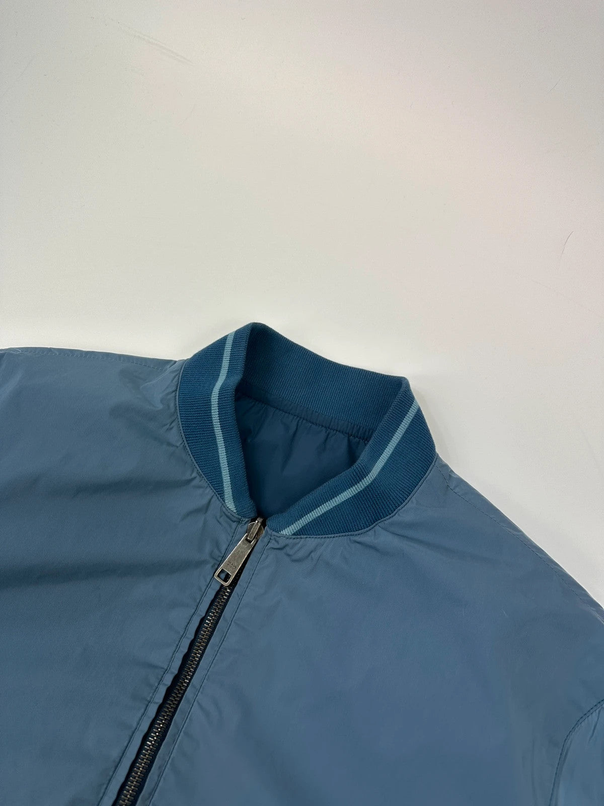 Prada blue reversible bomber jacket, nylon material, featuring logo and sleek minimalist design.