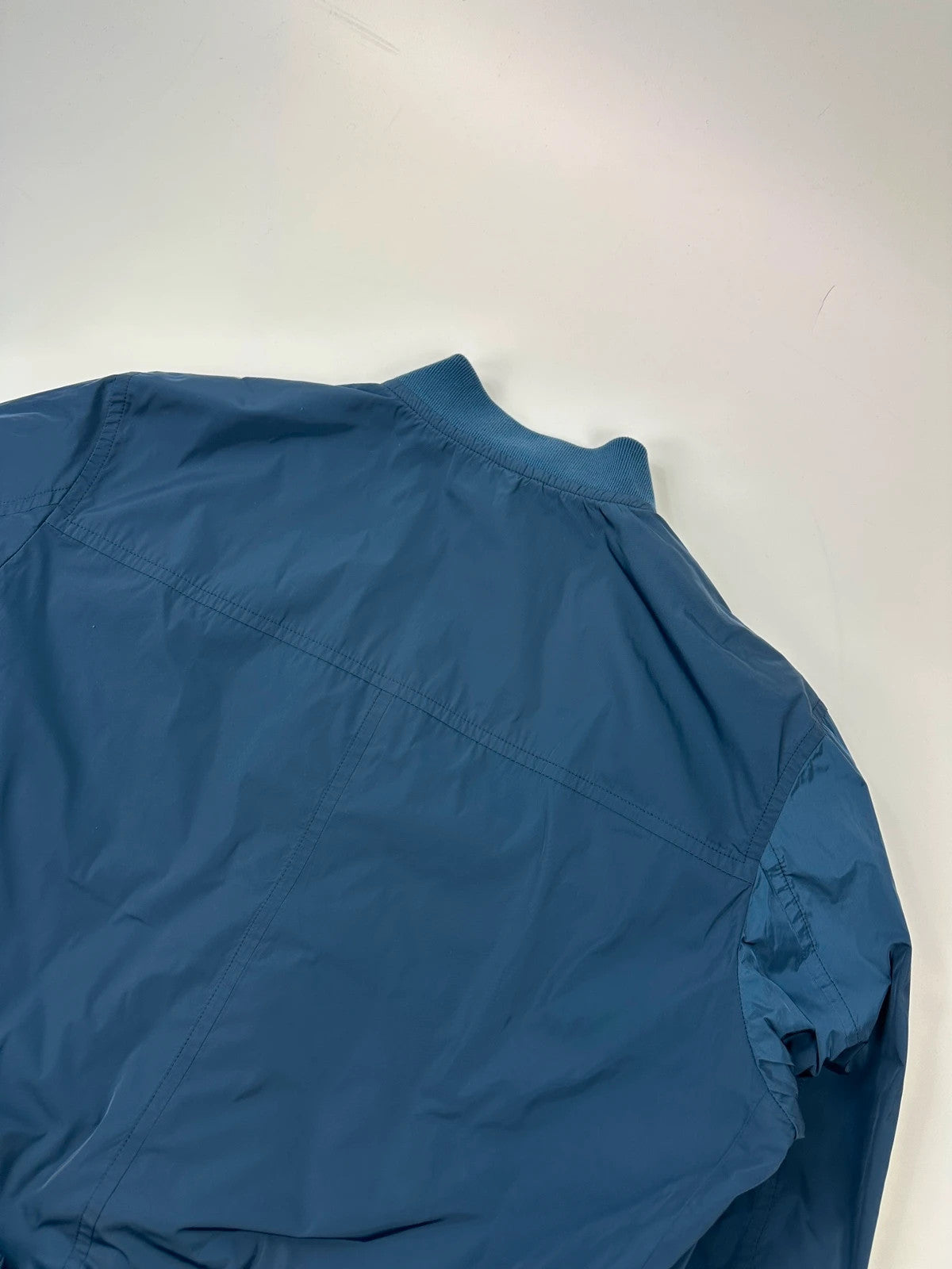 Prada blue reversible bomber jacket, nylon material, featuring logo and sleek minimalist design.