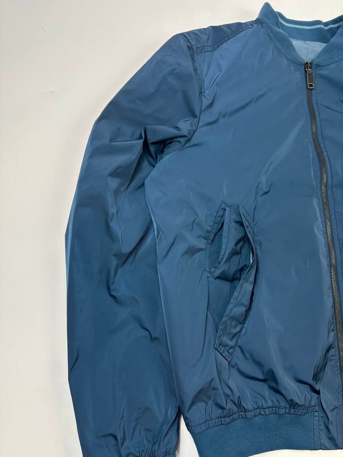 Prada blue reversible bomber jacket, nylon material, featuring logo and sleek minimalist design.