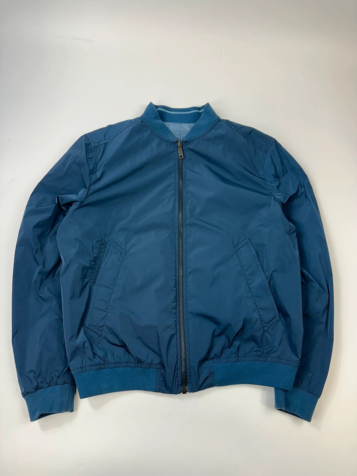 Prada blue reversible bomber jacket, nylon material, featuring logo and sleek minimalist design.