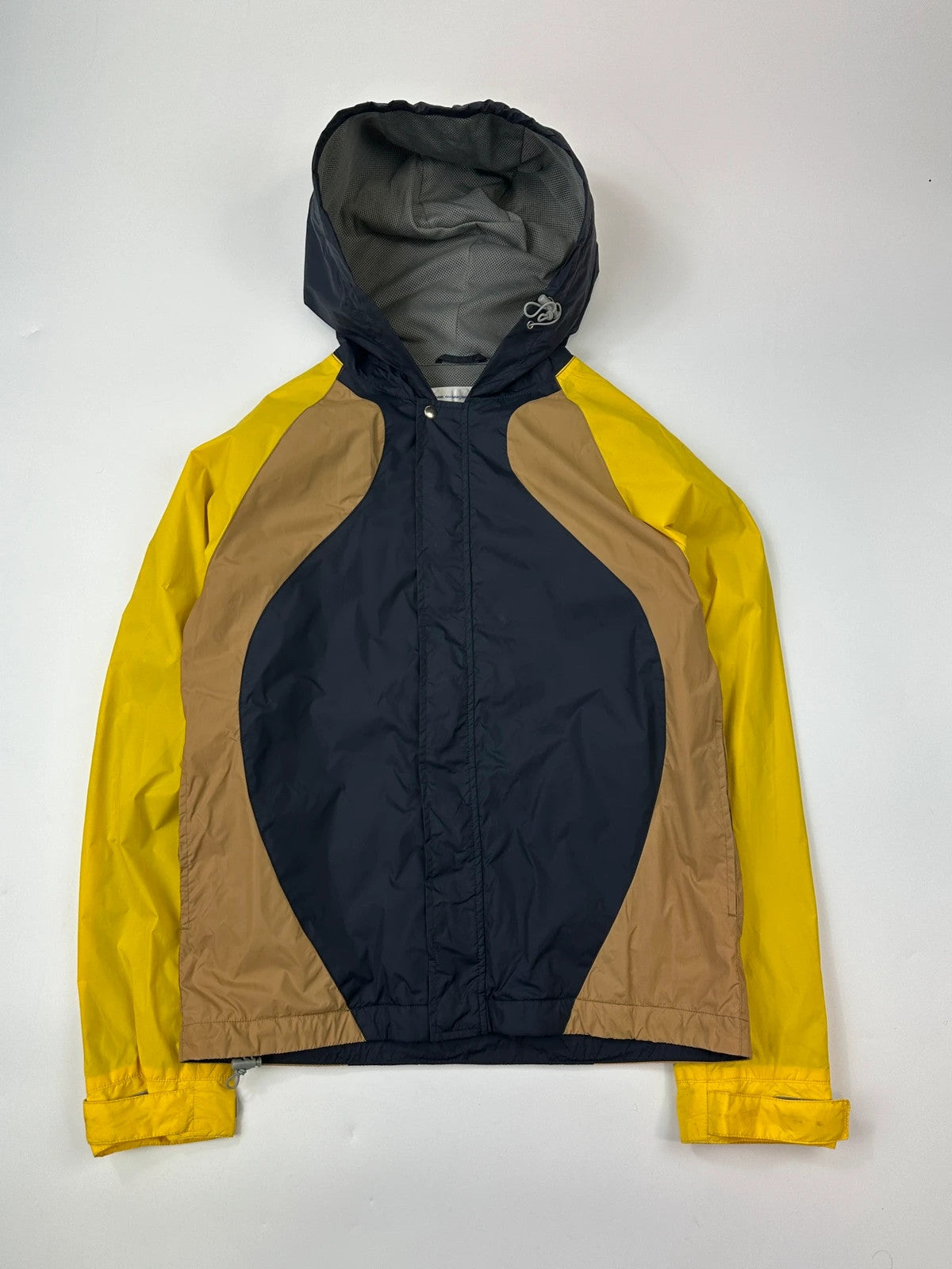 Comme Des Garçons navy and yellow block nylon hooded jacket with logo detail.