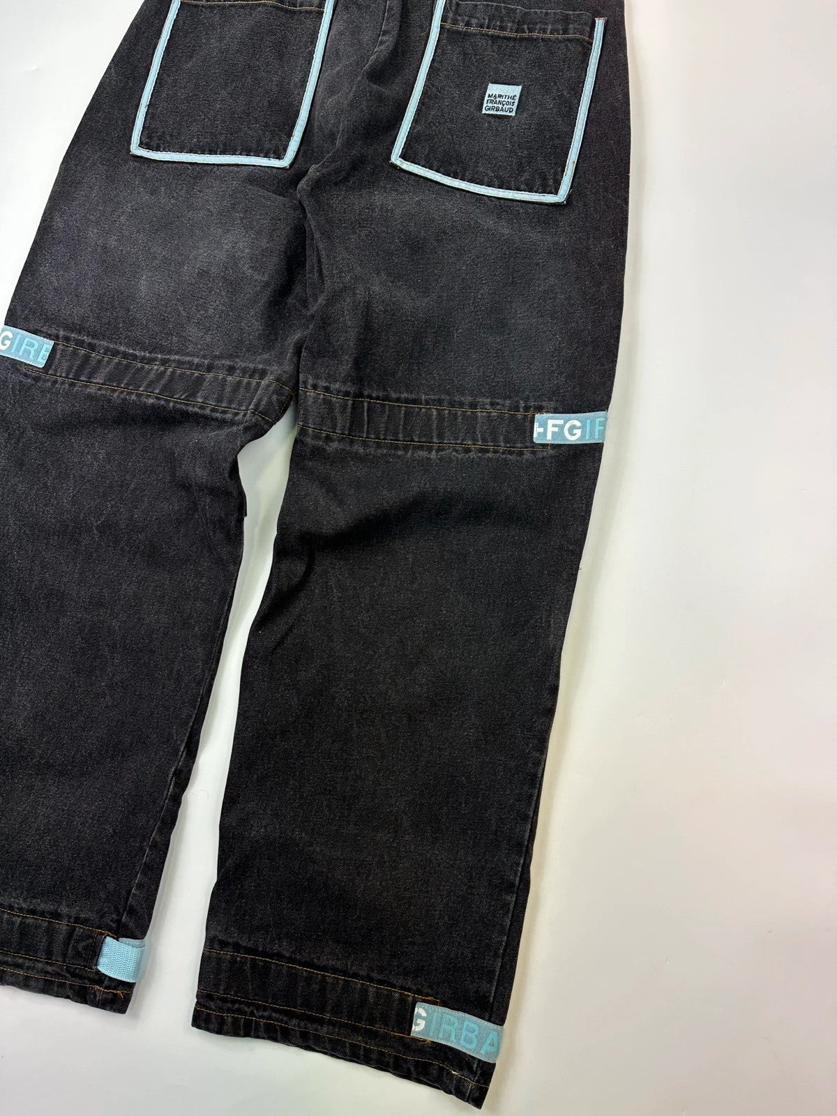 Marithé François Girbaud black and turquoise baggy denim trousers with cargo pockets and velcro details.