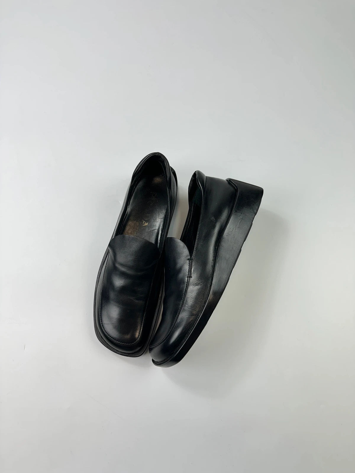 Prada black leather platform loafers with minimalist design and archival style from SS1998.