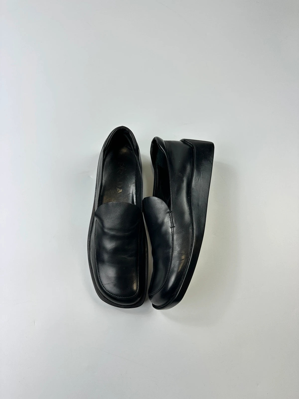 Prada black leather platform loafers with minimalist design and vintage 1998 collection details.