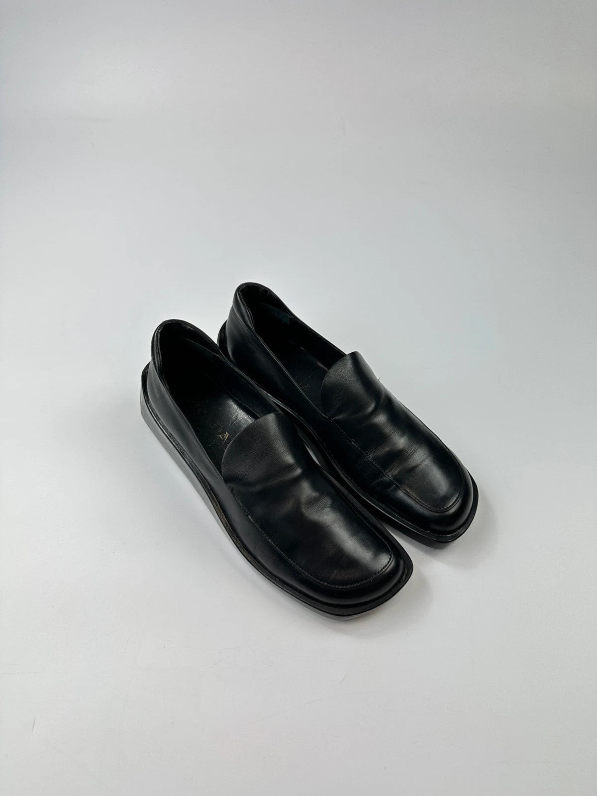 Prada black leather platform loafers with minimalist design and vintage 1998 collection details.
