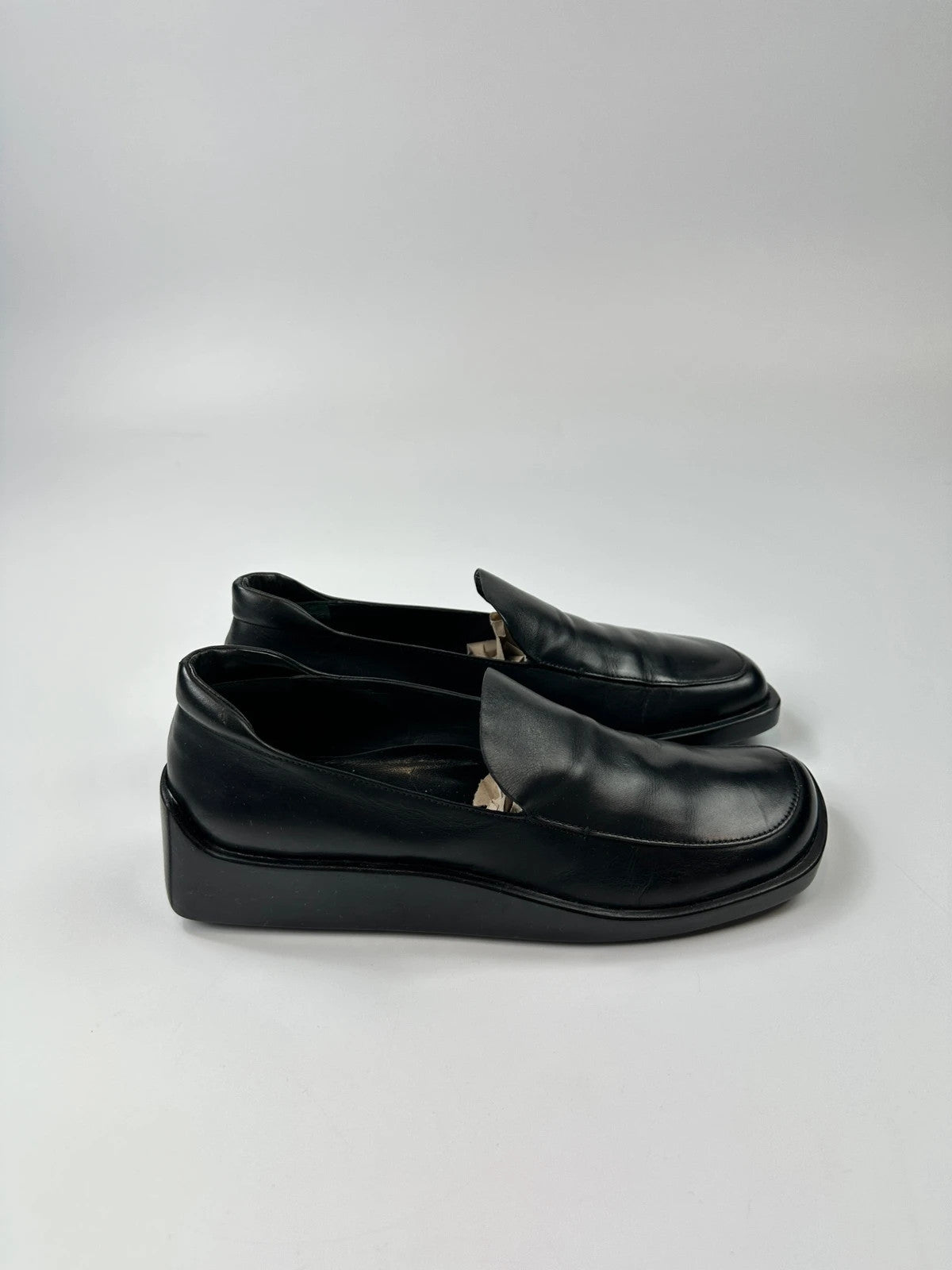 Prada black leather platform loafers with minimalist design and vintage 1998 collection details.