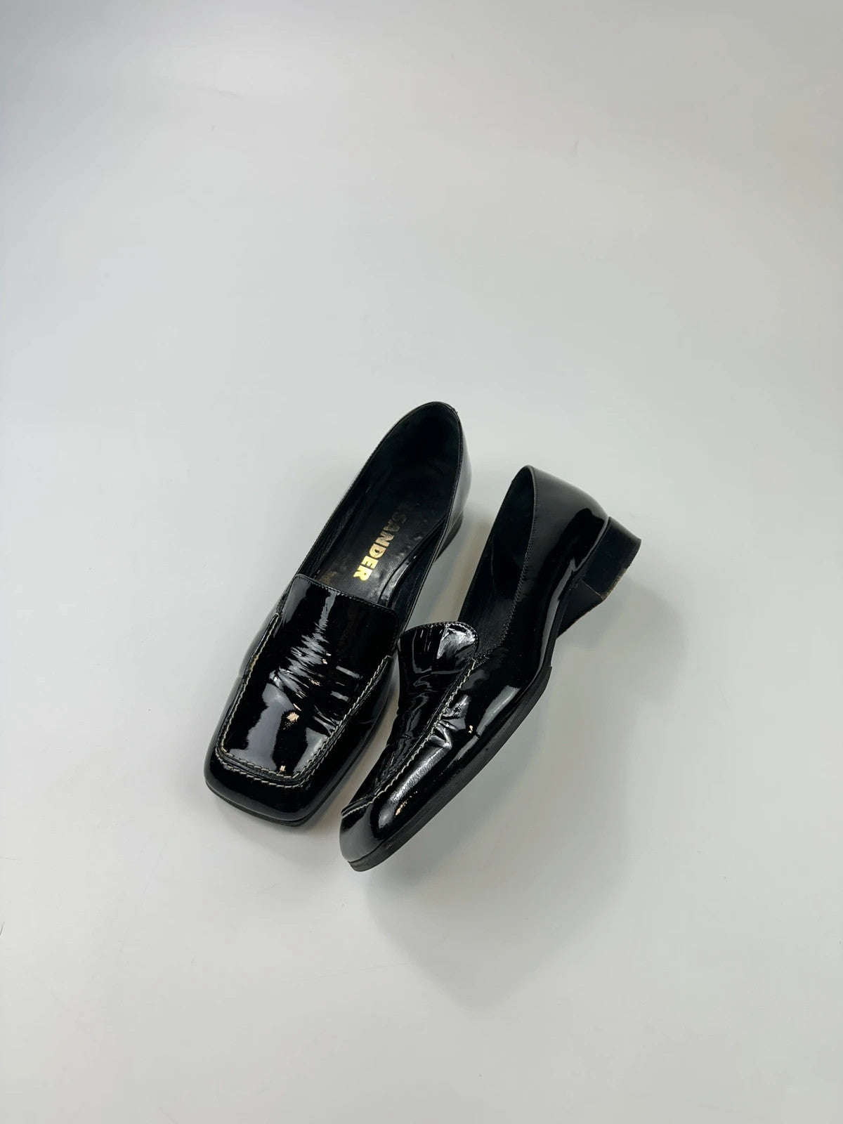Jil Sander black patent leather loafers with shiny finish and minimalist design.