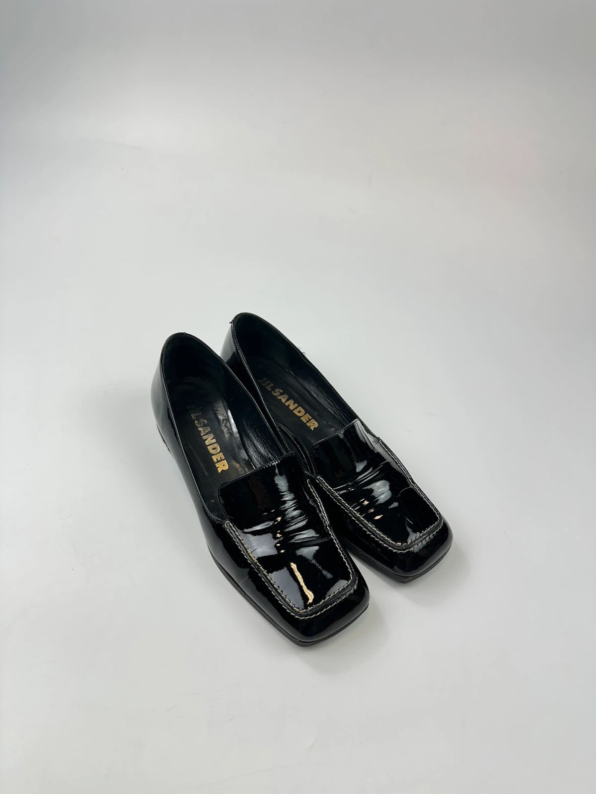 Jil Sander black patent leather loafers with shiny finish and minimalist design.