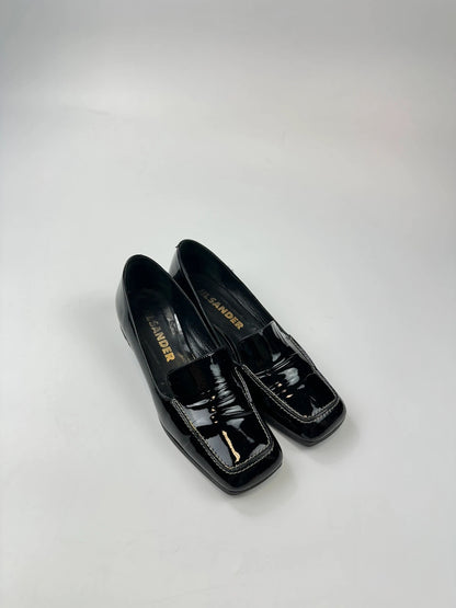 Jil Sander black patent leather loafers with shiny finish and minimalist design.