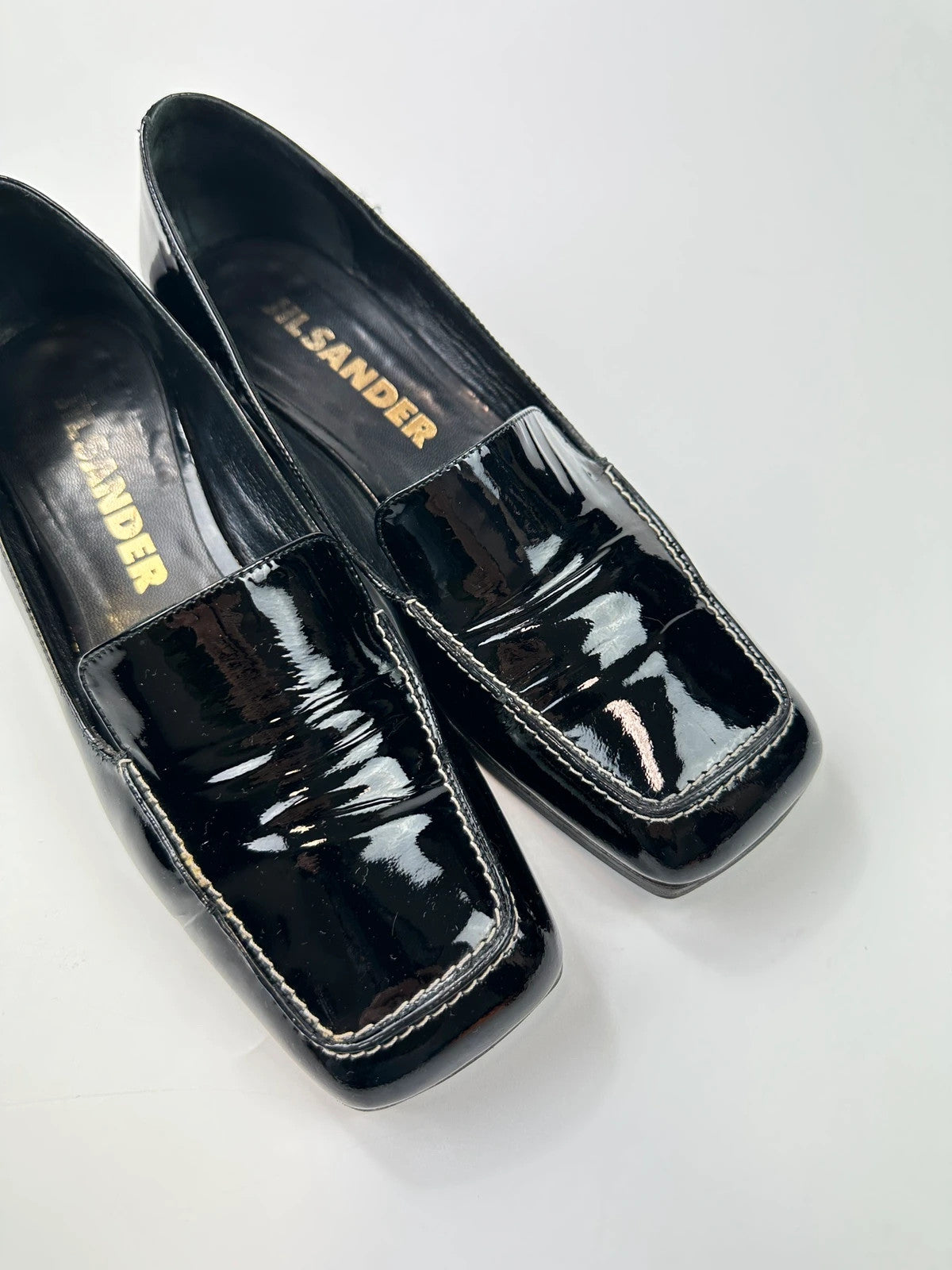 Jil Sander black patent leather loafers with shiny finish and minimalist design.