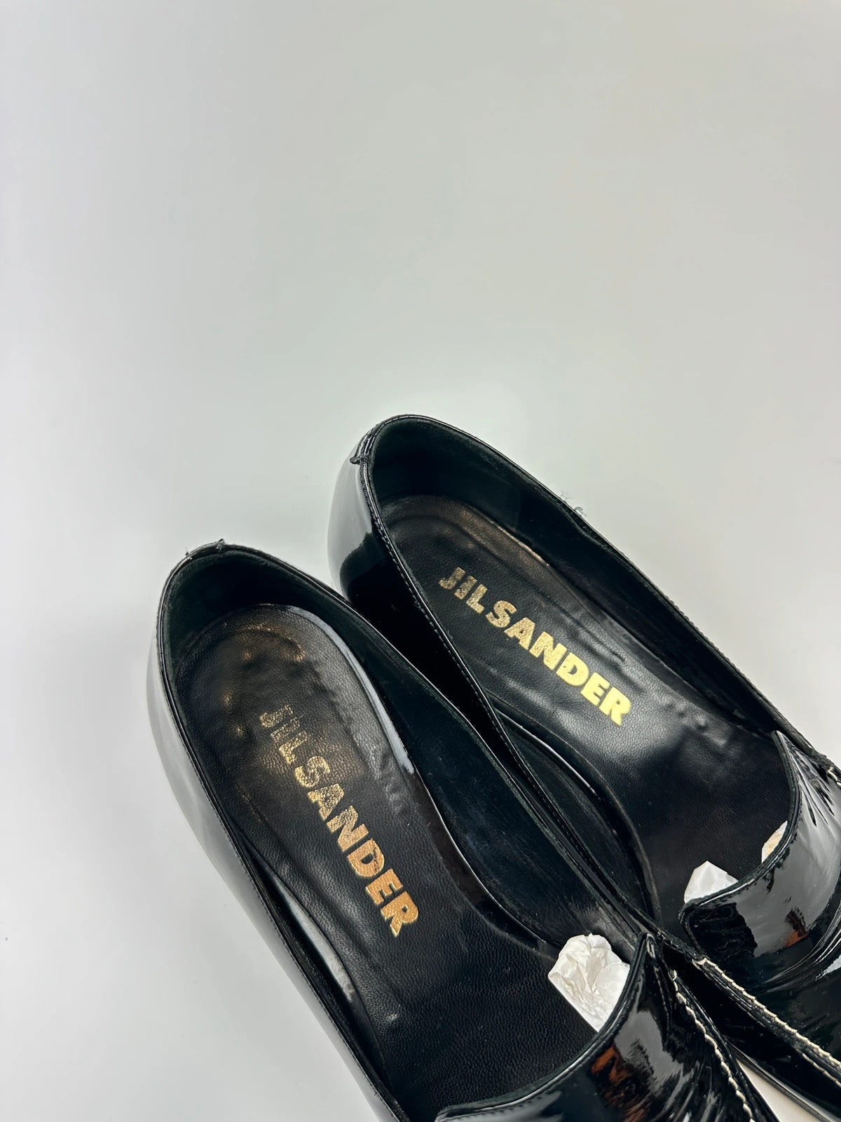 Jil Sander black patent leather loafers with shiny finish and minimalist design.