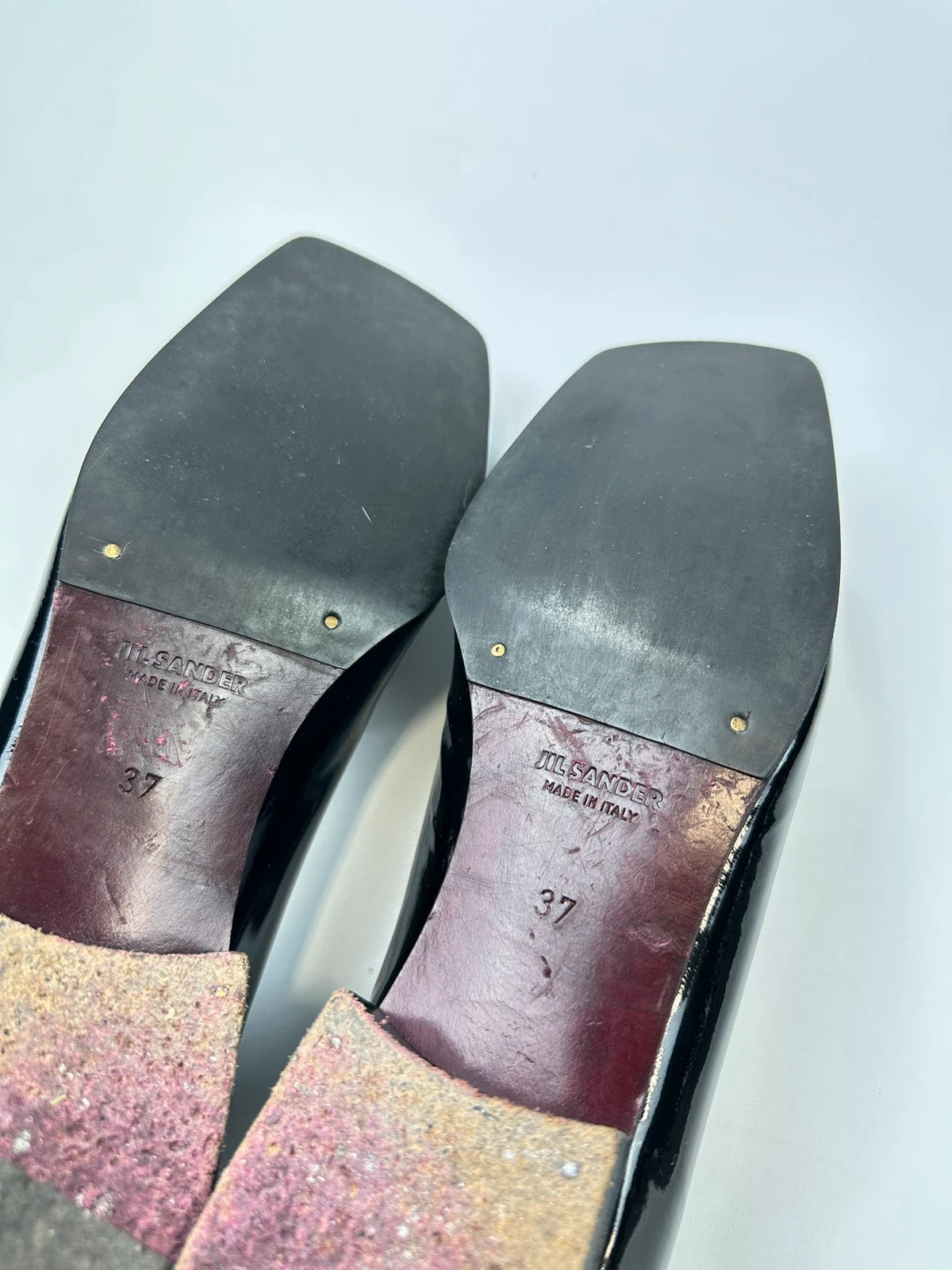 Jil Sander black patent leather loafers with shiny finish and minimalist design.