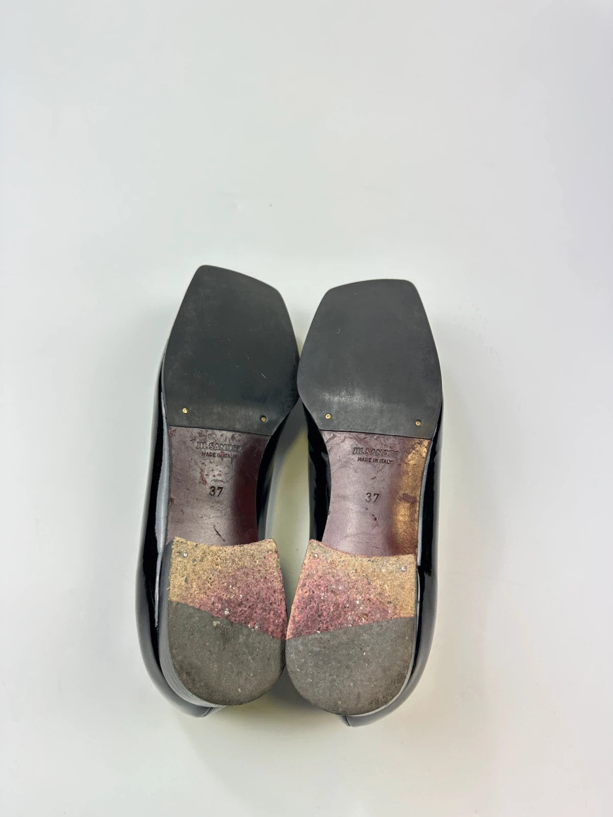 Jil Sander black patent leather loafers with shiny finish and minimalist design.