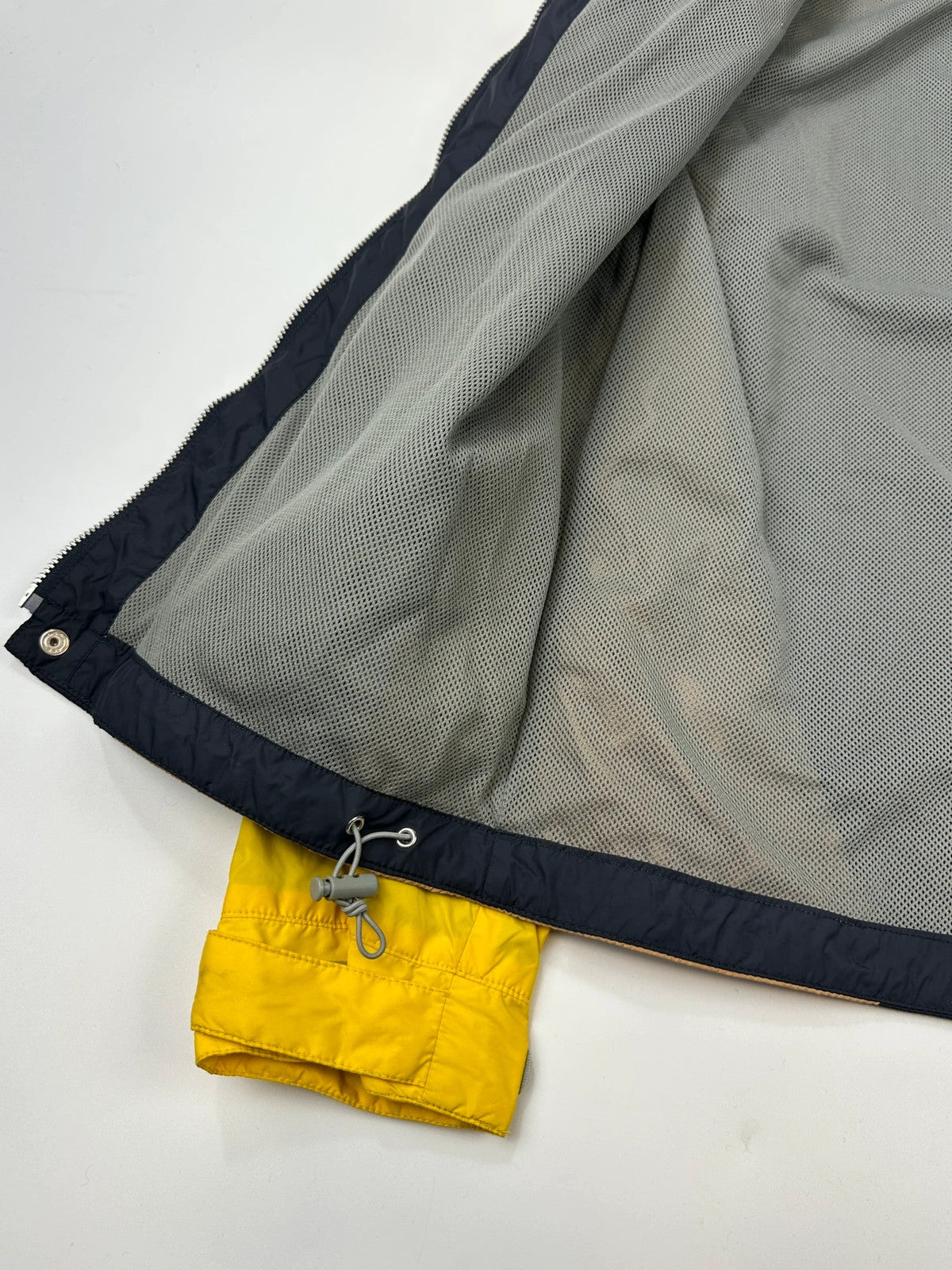 Comme Des Garçons navy and yellow block nylon hooded jacket with logo detail.