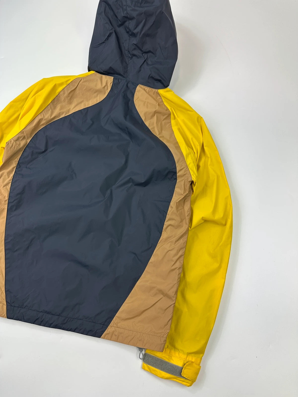 Comme Des Garçons navy and yellow block nylon hooded jacket with logo detail.