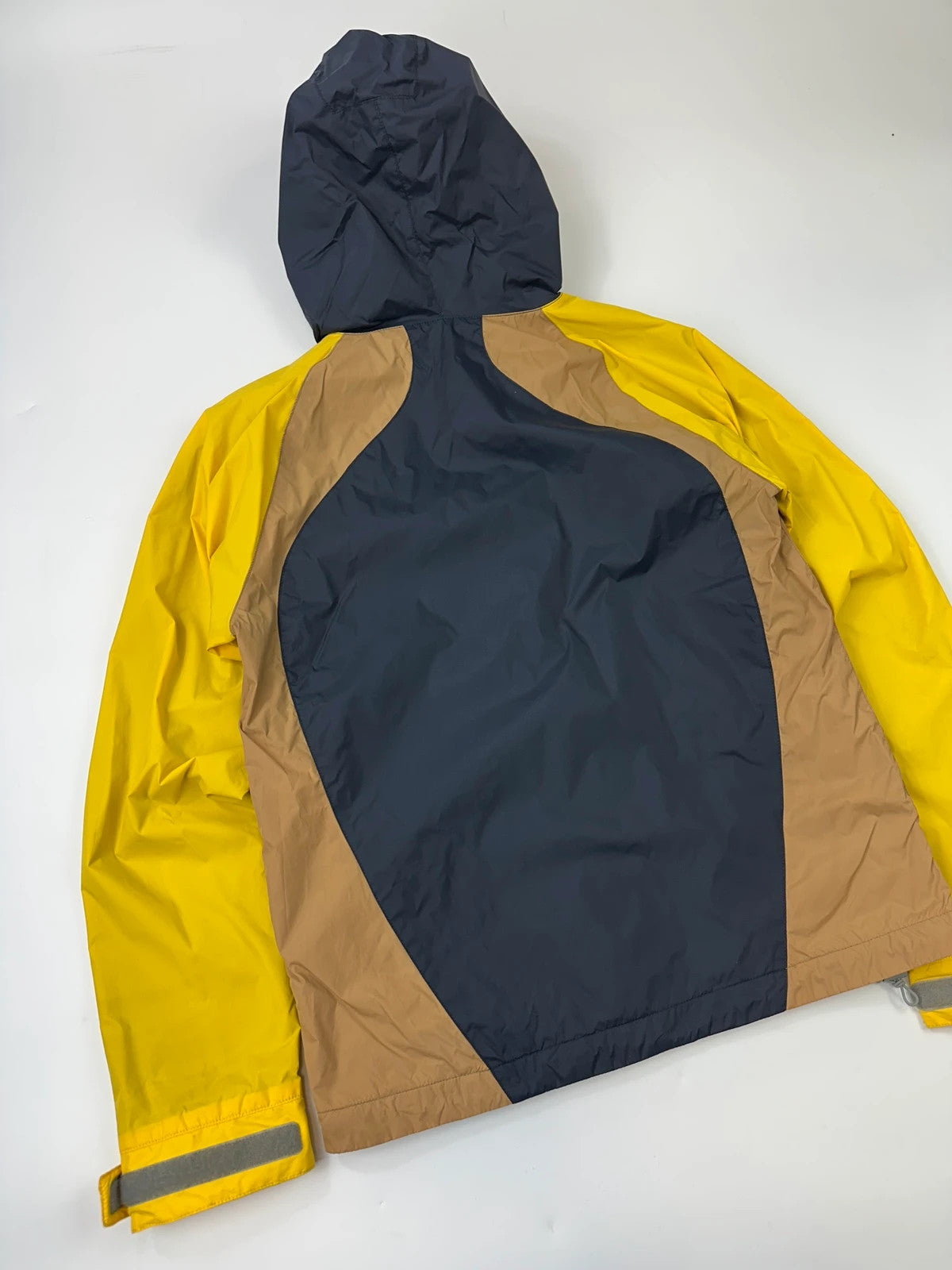Comme Des Garçons navy and yellow block nylon hooded jacket with logo detail.