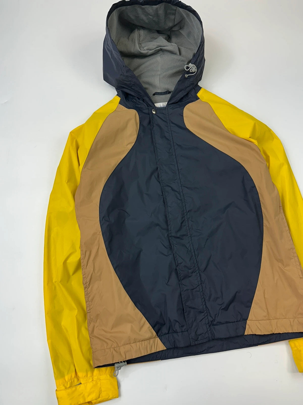 Comme Des Garçons navy and yellow block nylon hooded jacket with logo detail.