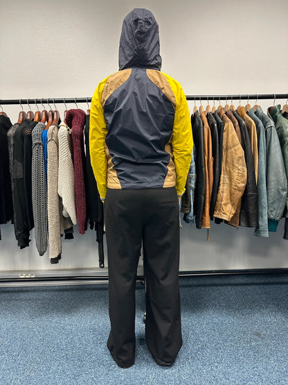 Comme Des Garçons navy and yellow block nylon hooded jacket with logo detail.