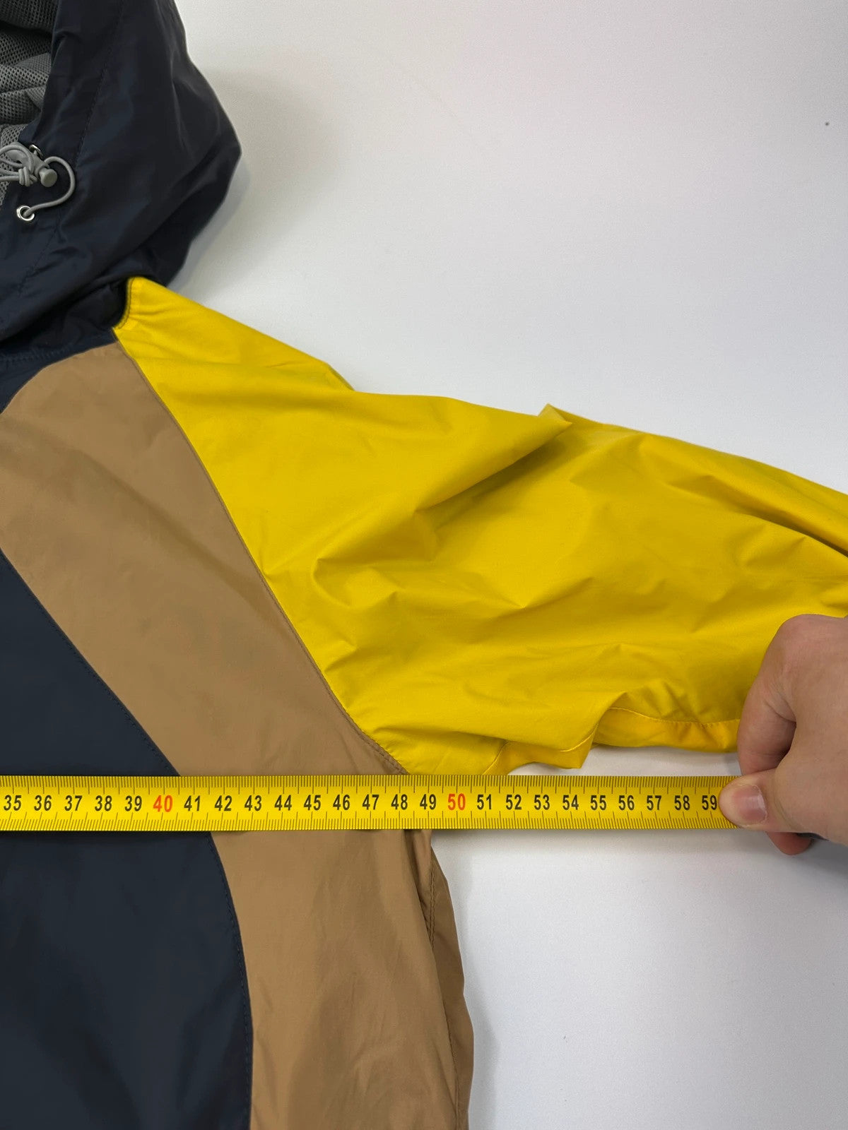 Comme Des Garçons navy and yellow block nylon hooded jacket with logo detail.