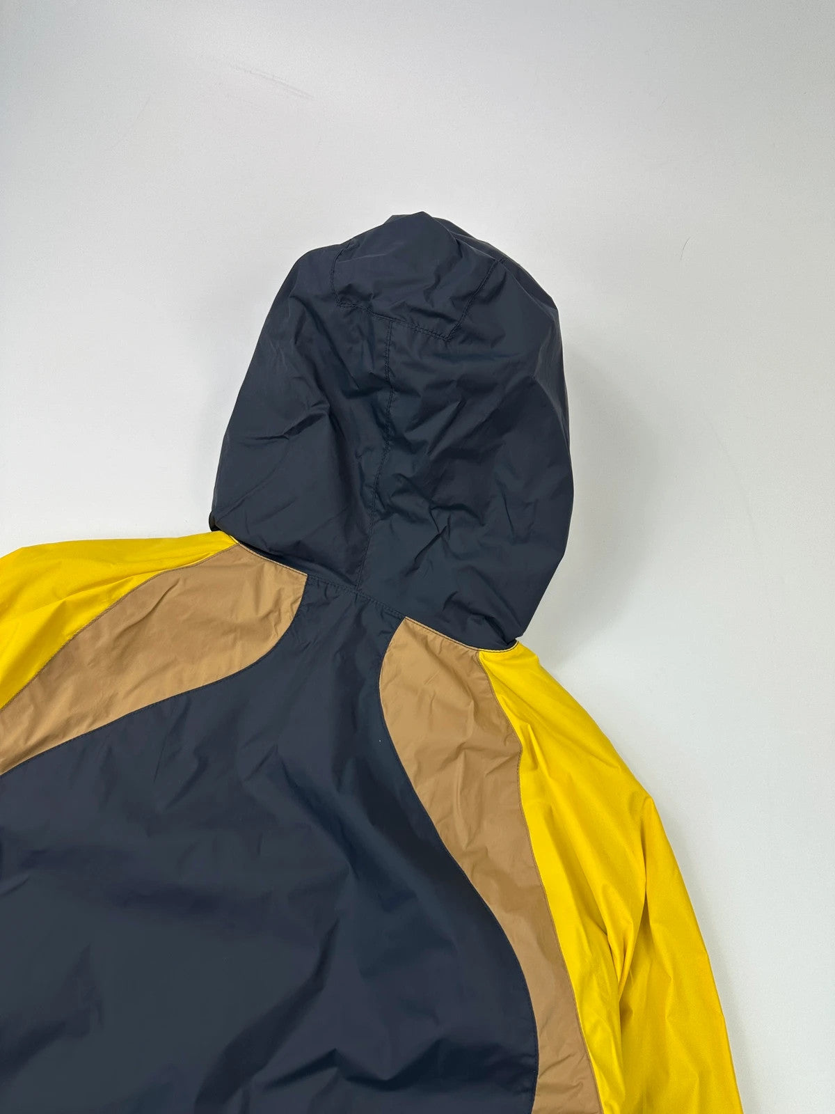 Comme Des Garçons navy and yellow block nylon hooded jacket with logo detail.