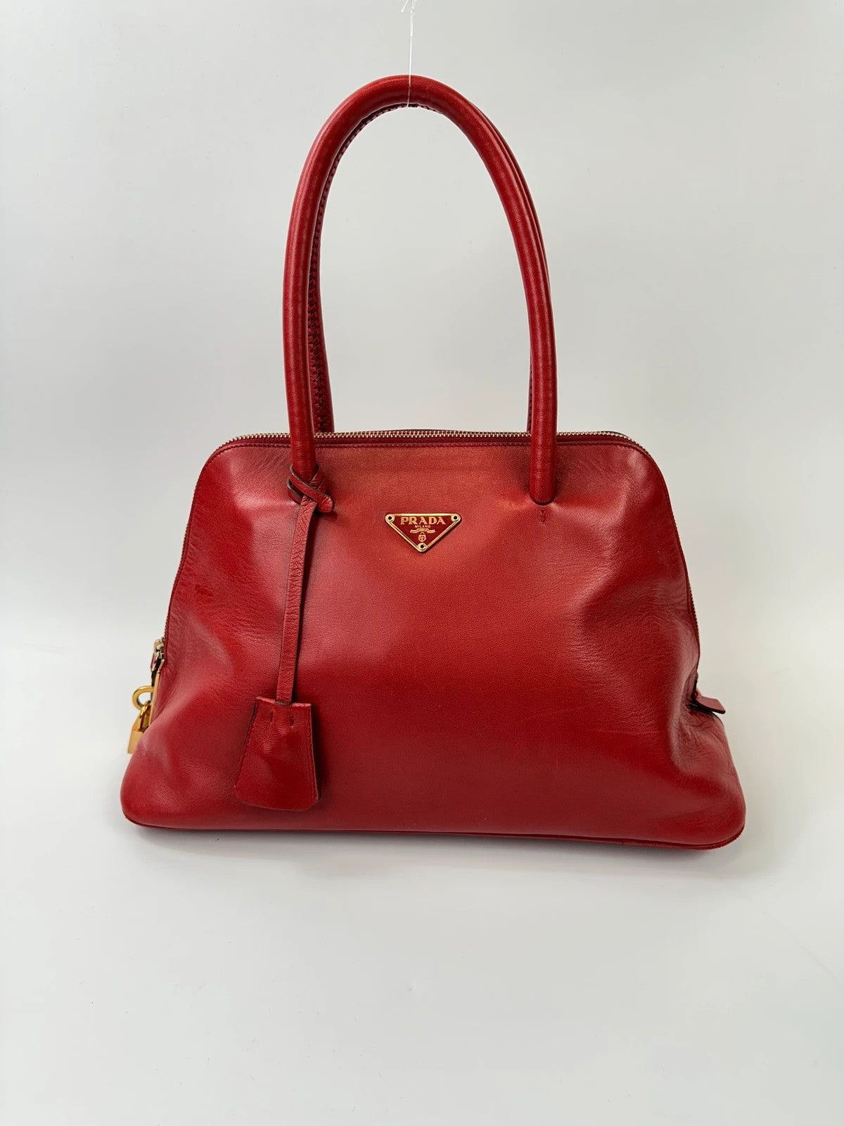 Prada red leather handbag with gold hardware and logo detail, vintage Y2K style.