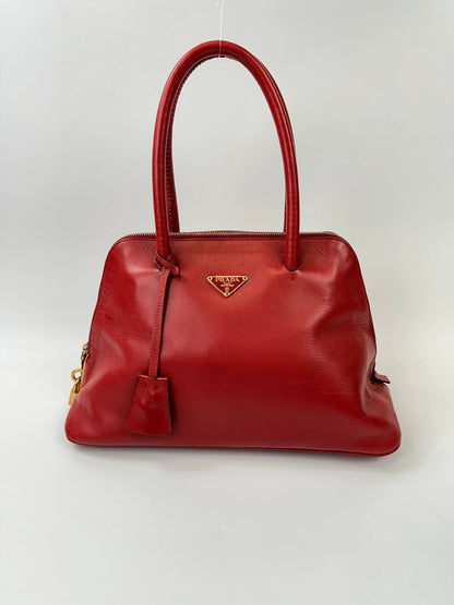 Prada red leather handbag with gold hardware and logo detail, vintage Y2K style.