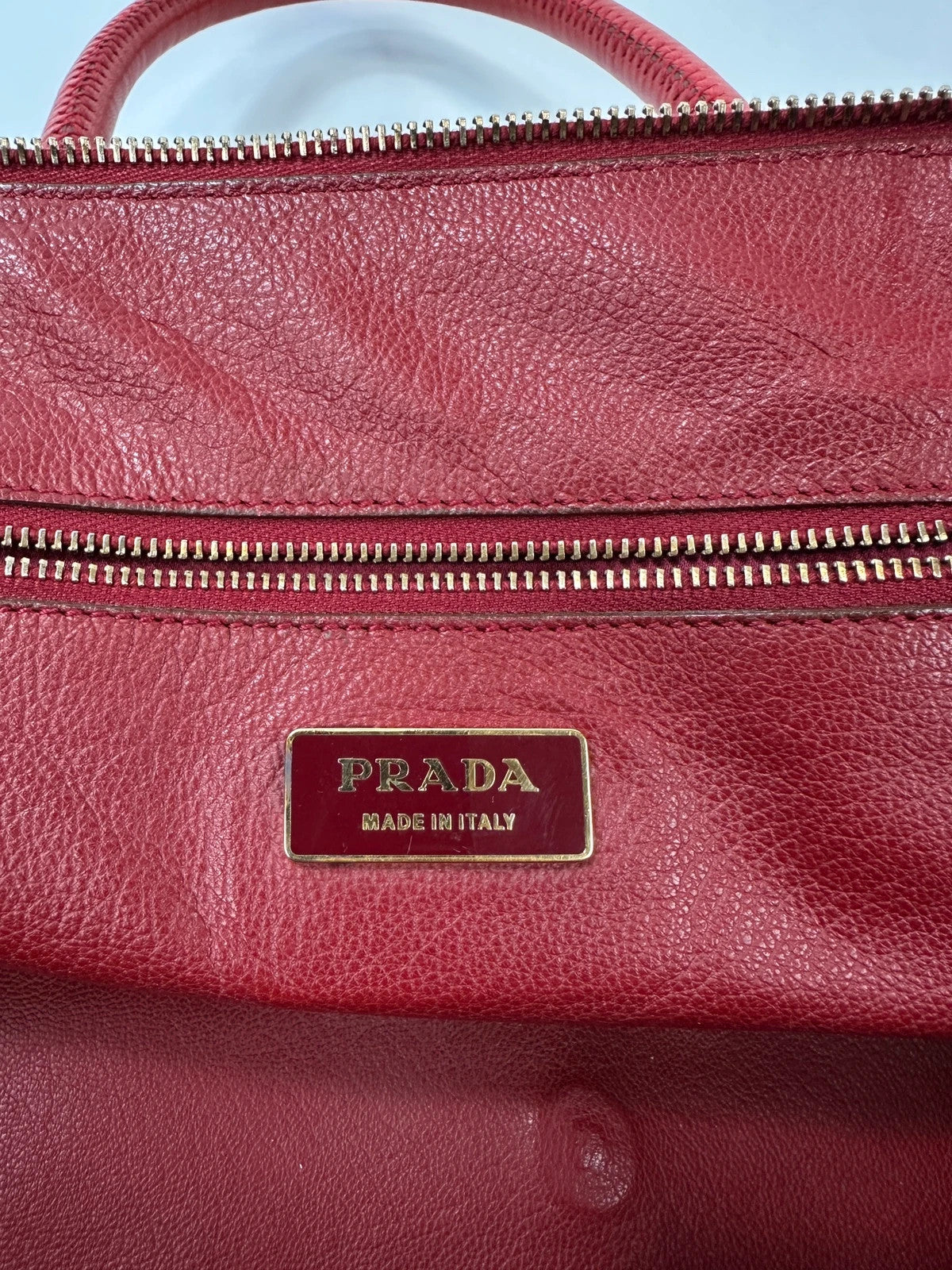 Prada red leather handbag with gold hardware and vintage logo detail.