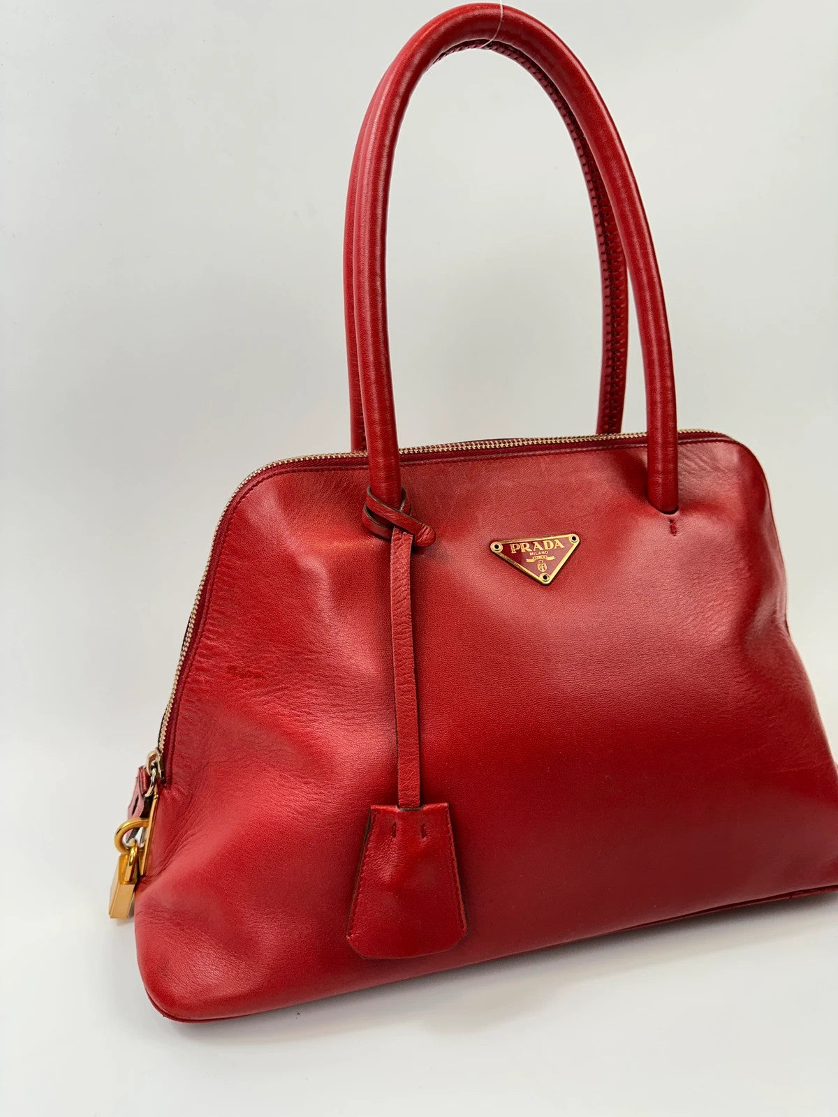 Prada red leather handbag with gold hardware and vintage logo detail.