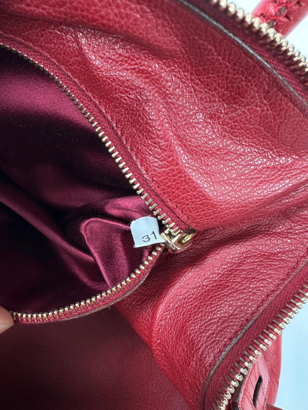 Prada red leather handbag with gold hardware and vintage logo detail.