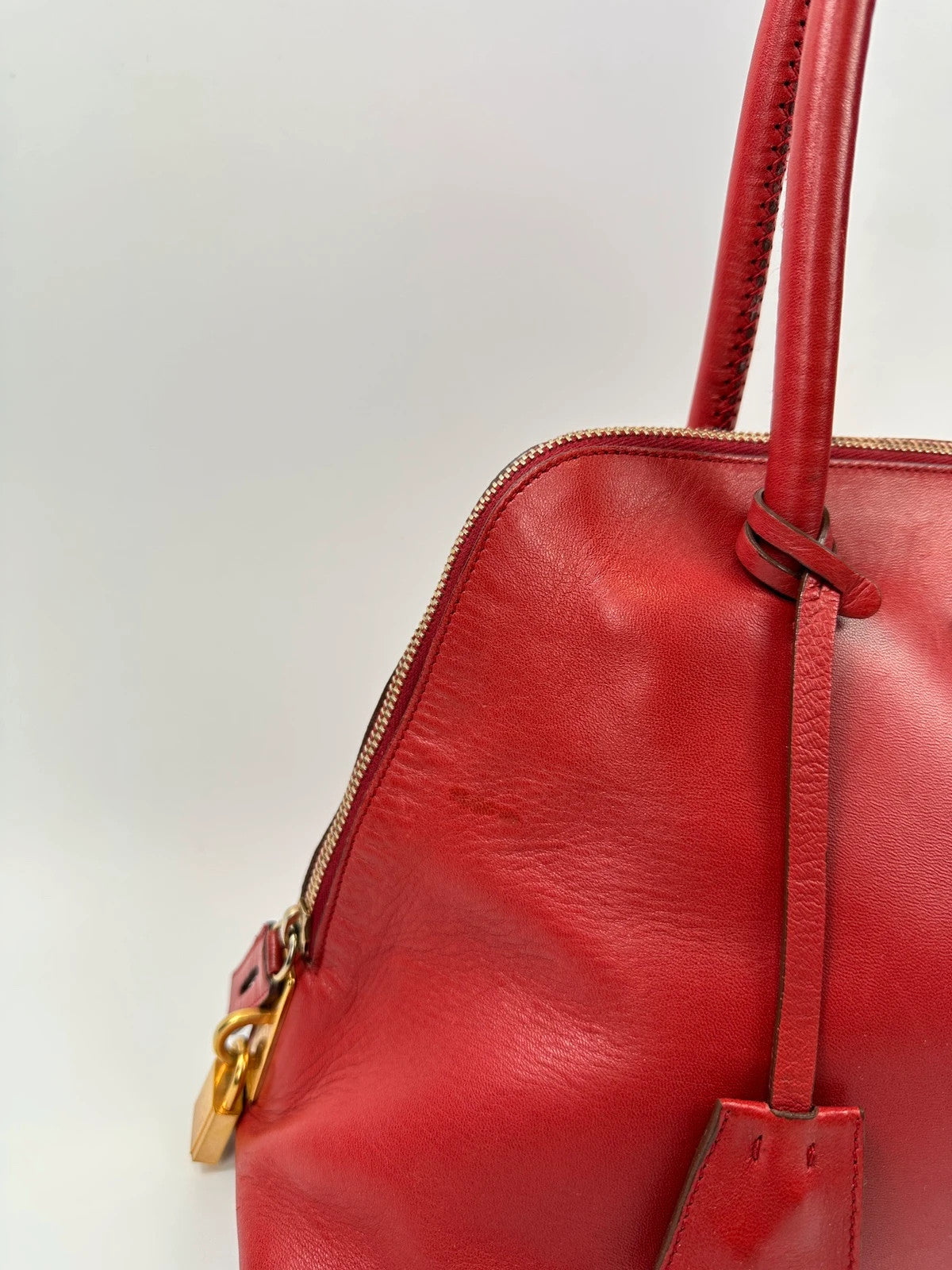 Prada red leather handbag with gold hardware and vintage logo detail.