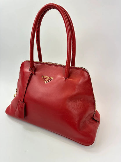 Prada red leather handbag with gold hardware and vintage logo detail.