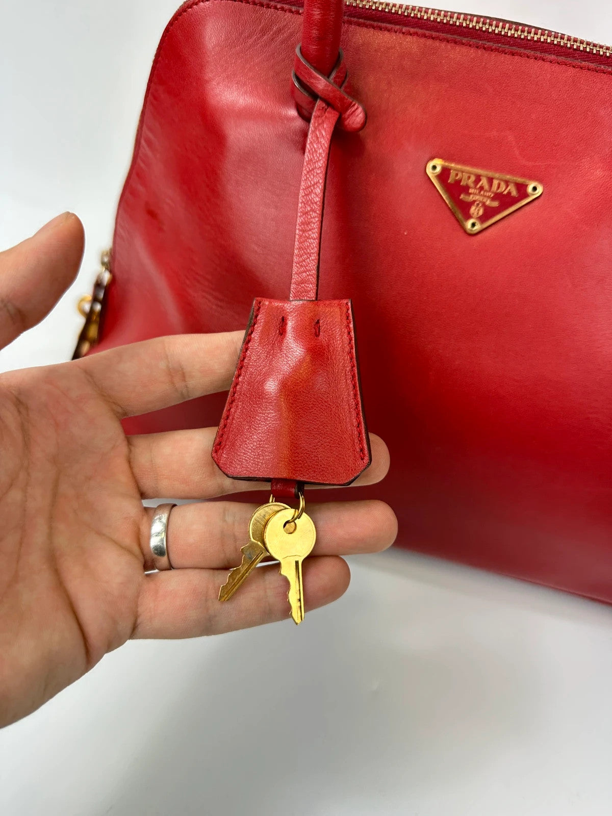 Prada red leather handbag with gold hardware and vintage logo detail.
