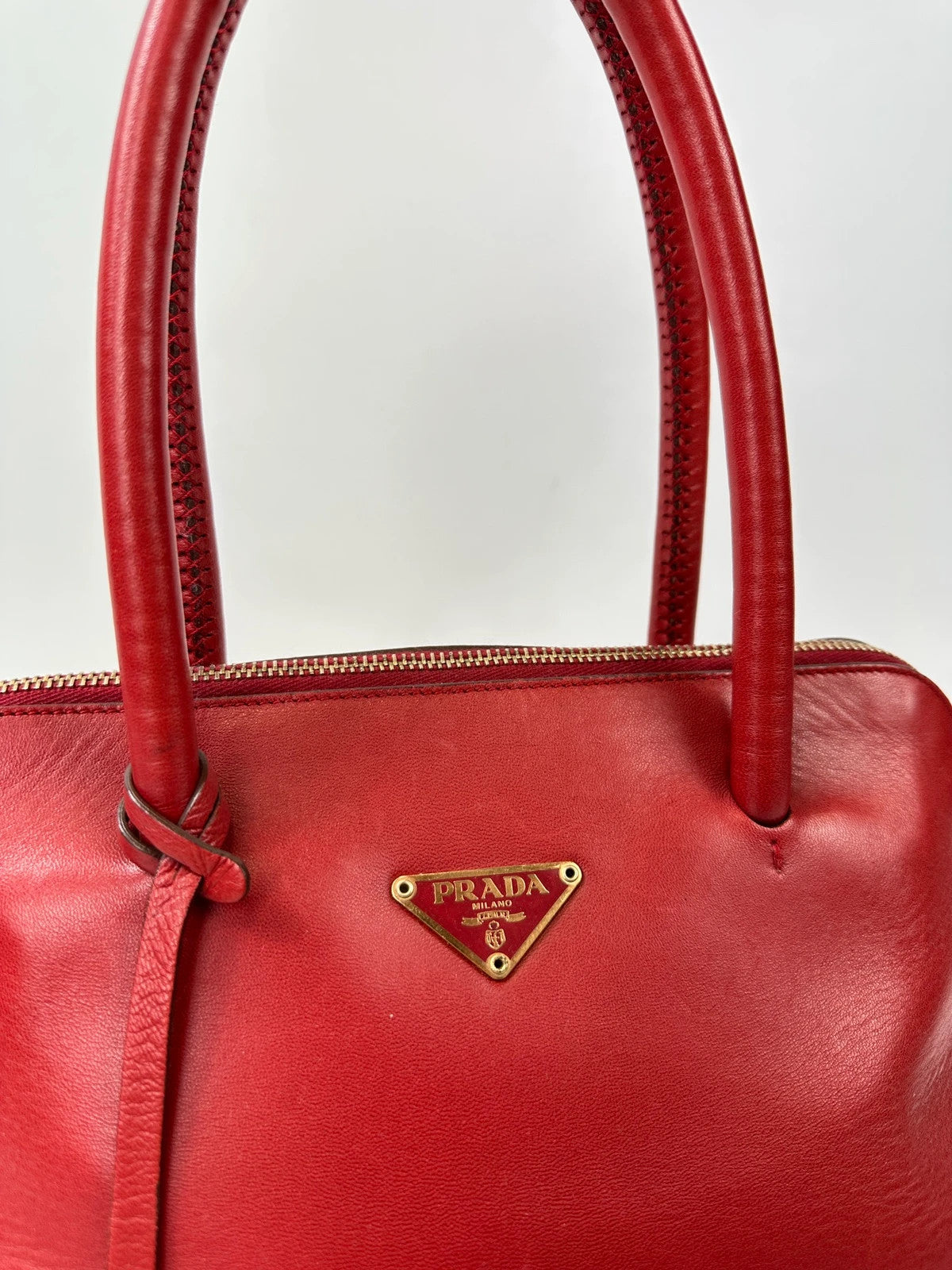 Prada red leather handbag with gold hardware and vintage logo detail.