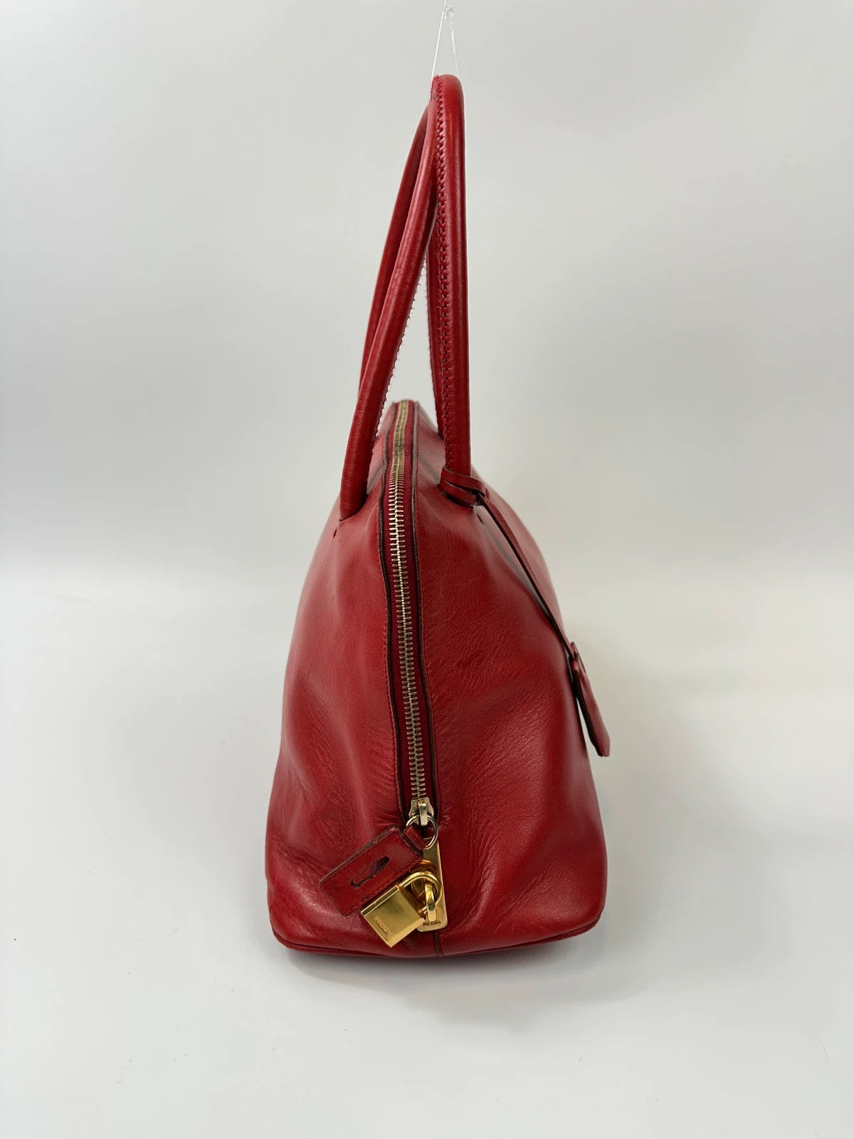 Prada red leather handbag with gold hardware and vintage logo detail.