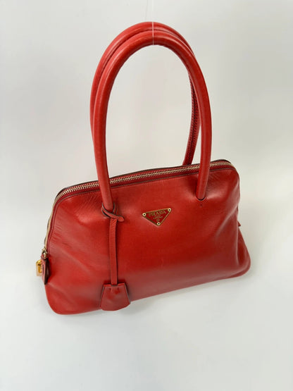 Prada red leather handbag with gold hardware and vintage logo detail.