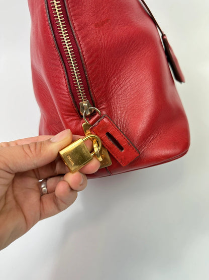Prada red leather handbag with gold hardware and vintage logo detail.
