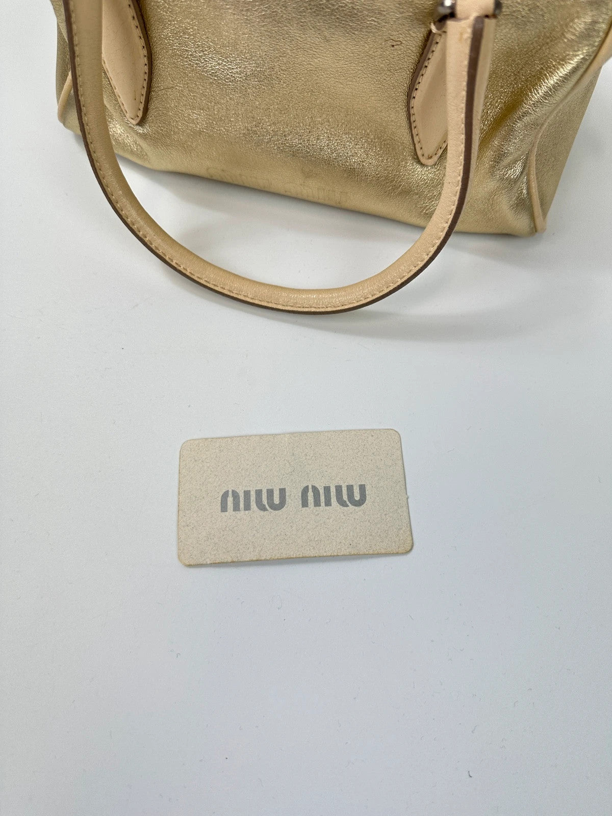Miu Miu gold leather mini handbag with shiny glitter finish and logo detail.