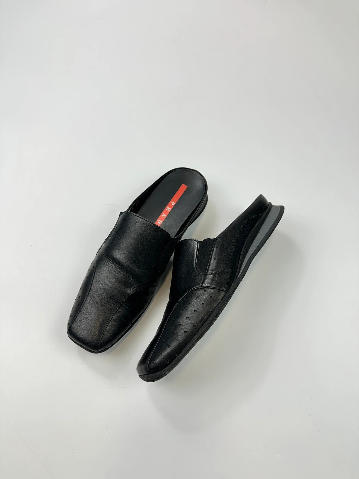 Prada black leather mules with ventilation, minimalist design from SS99 collection.