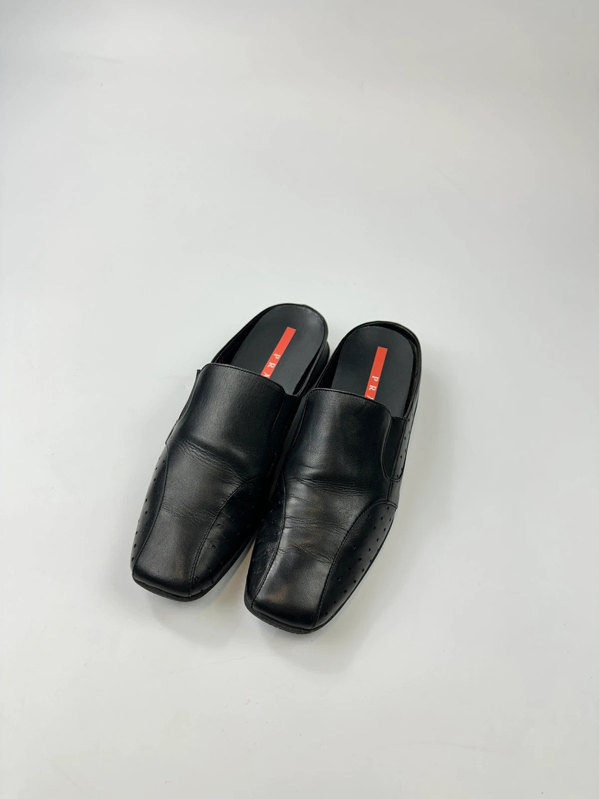 Prada black leather mules with ventilation, minimalist design from SS99 collection.