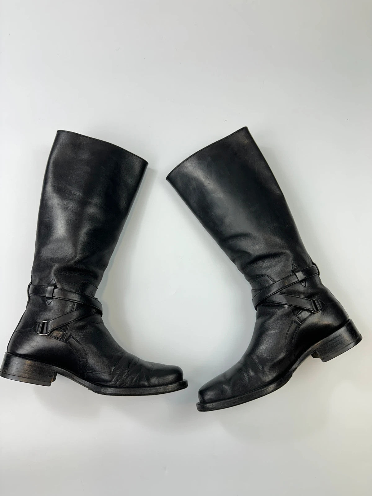 Prada black leather knee-high boots with high belt detail and minimalist design.