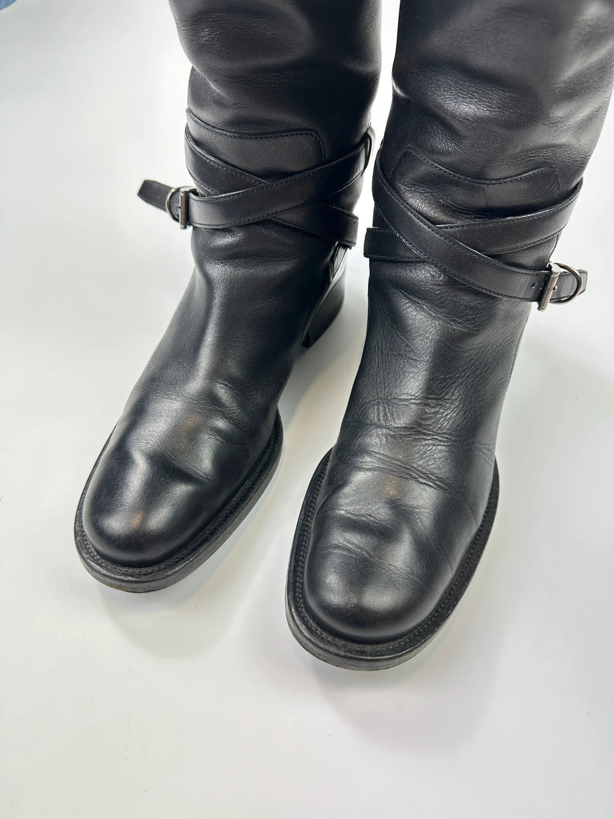 Prada black leather knee-high boots with high belt detail and minimalist design.